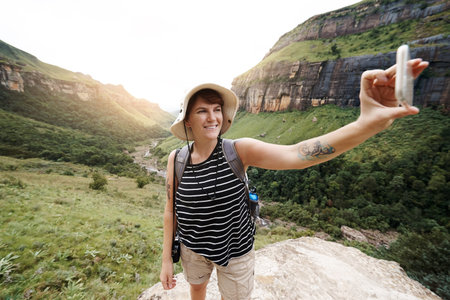 Shot of a young woman taking a selfie while out on a hike through the mountainsの写真素材