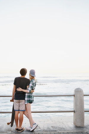 Rearview shot of an affectionate young couple standing on the promenade