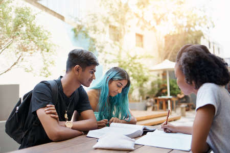 Shot of a group of young students enjoying a break outdoors on campusの写真素材
