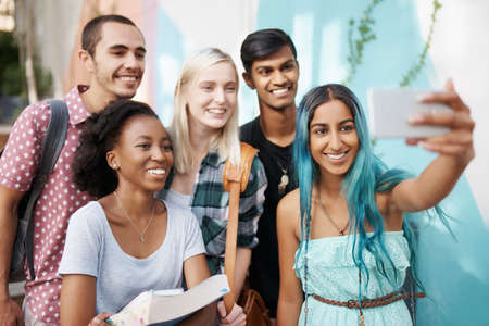 Shot of a group of young students enjoying a break outdoors on campusの写真素材