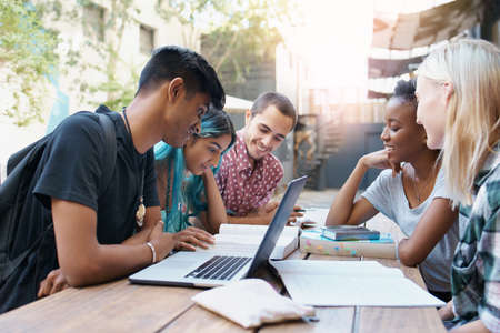 Shot of a group of young students enjoying a break outdoors on campusの写真素材