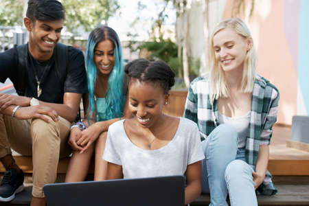 Shot of a group of young students enjoying a break outdoors on campusの写真素材