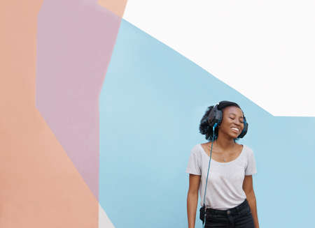 Shot of a cheerful young woman dancing outside and listening to music on her phone with her eyes closedの写真素材