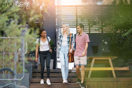 Shot of a group of happy young friends walking together outside on campusの写真素材