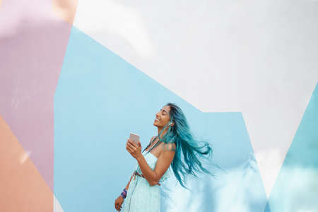 Shot of a cheerful young woman dancing and listening to music outside on her phoneの写真素材