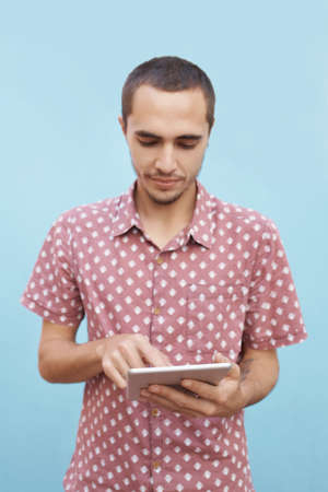Shot of a focused young student standing outside and working on his tablet before classの写真素材