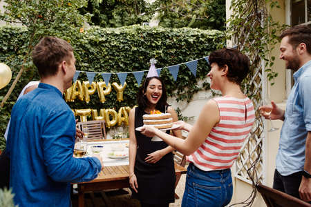 Cropped shot of a group of friends celebrating a birthday outdoorsの写真素材