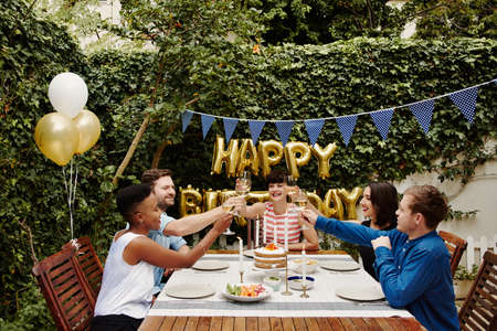 Cropped shot of a group of friends toasting while celebrating a birthday outdoorsの写真素材