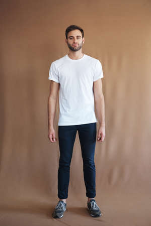 Shot of a handsome young man posing against a brown backgroundの写真素材