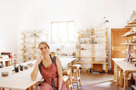 Portrait of a beautiful young woman wearing a apron in her workshopの写真素材