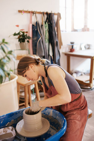 Shot of a woman molding clay on a pottery wheel