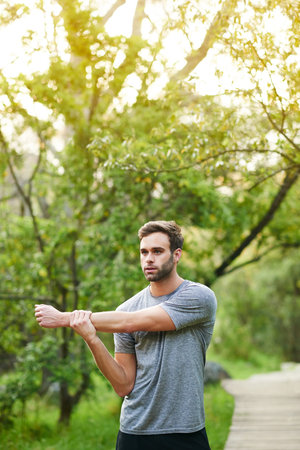 Cropped shot of a young man stretching before his run in a park