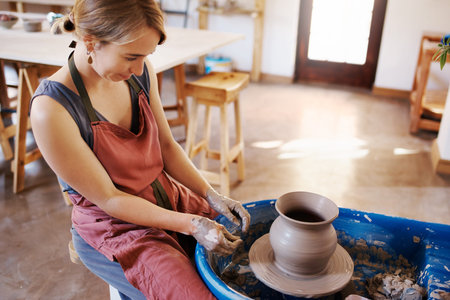 Shot of a woman molding clay on a pottery wheel