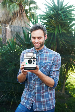 Shot of a handsome young man taking photographs while out in natureの写真素材