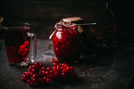 hot tea made from cranberry. Homemade jam in a glass jar on a dark background. Winter christmas drinkの写真素材