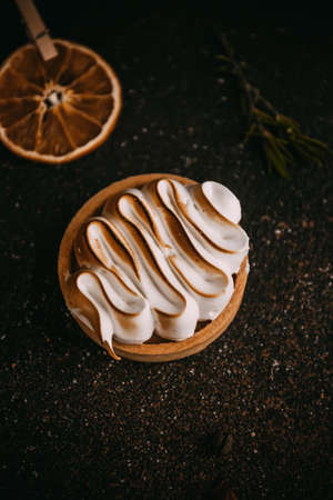 Lemon tartlet with meringue on the stone dark table with orangeの写真素材