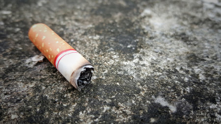 Cigarette stub isolated on the cement  floor background with copy space.Cigarette smoking is a...