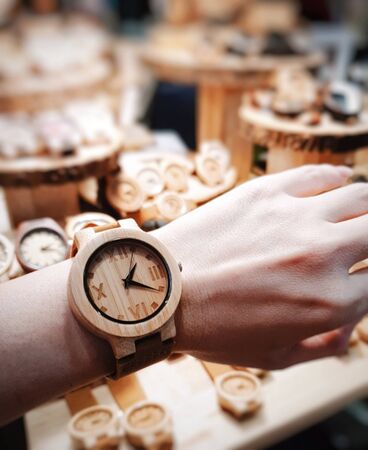 The round shape watch shows Roman numerals made from wood, worn on the wrist of women at 13.21 minutesの写真素材