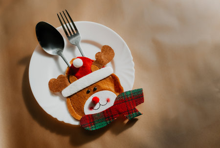 Preparation for the festive feast: transformation of the Christmas table. Top view photo of plate, cutlery, napkin on brown background with advertising area. Copy space for text.の写真素材
