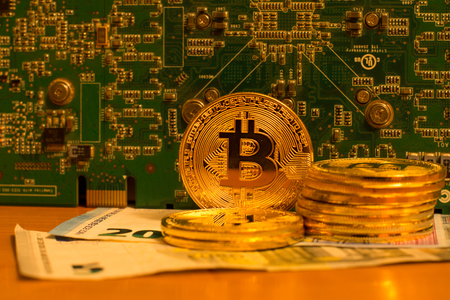 Bitcoin and other currency with a circuit board on backgroundの写真素材