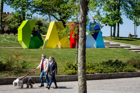 Two elder people walking a dog on an urban gardenの写真素材