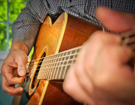 Image of a man playing an acoustic guitar.