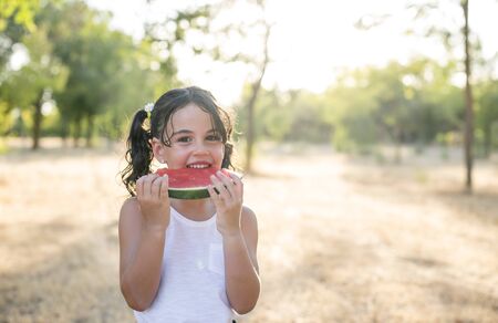Tasting a slice of watermelon at sunset in the parkの写真素材
