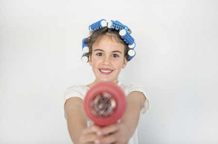 little girl posing with curlers and hair dryer, amazed and happyの写真素材