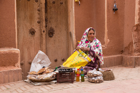 KASHAN, IRAN - MAY 2, 2015: an elderly woman in the ancient village of Abyaneh, near Kashan, in Iran. In background, the tipical red mud-brick houses of Abyaneh.のeditorial素材