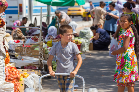 SAMARKAND, UZBEKISTAN - AUGUST 29, 2016: boy carries bread in the fruit and vegetable market in Samarkand, Uzbekistanのeditorial素材