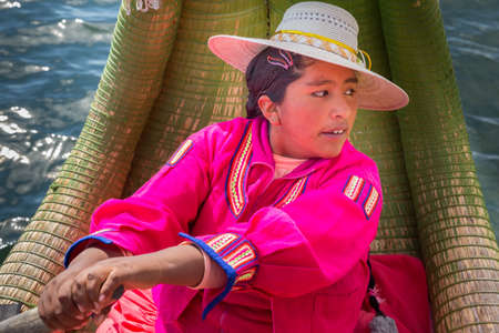 Puno, Peru - september 27, 2018: woman in traditional clothes rowing a uros totora boat in lake Titicaca, peruのeditorial素材
