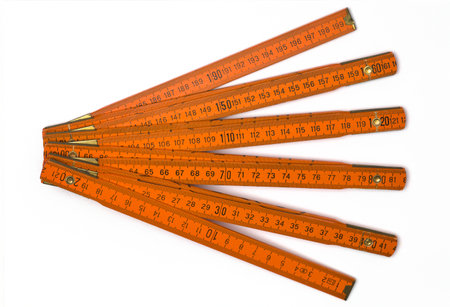 An orange folding ruler on the white surface: collapsible measuring tool with hinged segments for...