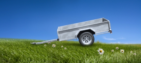 Empty trayler on the greeen meadow and blue sky background の写真素材