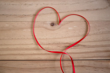 Red ribbon heart on wooden background, Valentines day conceptsの写真素材