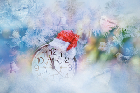 Clock with Santa hat on and Christmas decoration highlighted behind frosty patternの写真素材