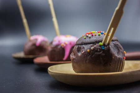 Close up sweet chocolate and handmade cake ball in the wooden ladles on black background.