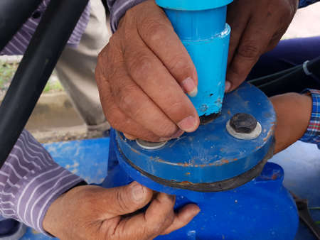 Hands of two men who helped assemble the flange bolts of the water pump.