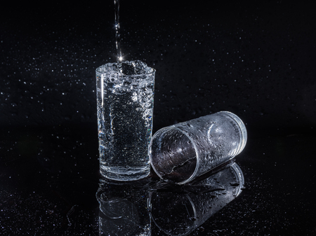 Water splash and crystal glass on black background.