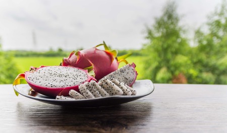 Dragon fruits healthy food in black dish on white wooden and nature  background.の写真素材