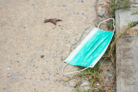 Disposable face mask on pavement dirty and causing the spread of pathogens.の写真素材
