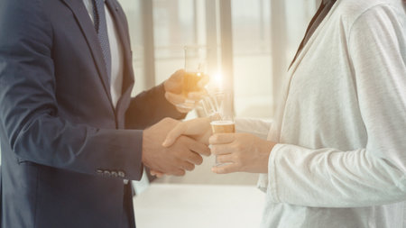 Business people shaking hands and drinking champagne to celebrate after the meeting.の写真素材