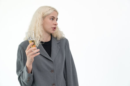 Portrait caucasian businesswoman wearing suit standing and holding a glass of champagne on white background.の写真素材