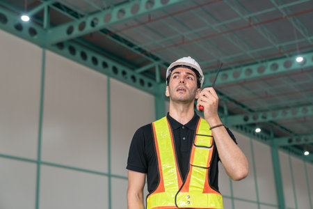 Male engineer wearing safety helmet wear reflective vest use communication tools Walkie Talkie Order work within the industry.の写真素材