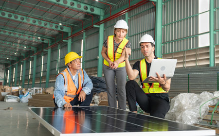Team of engineers and technicians working on solar panel in a large warehouse.