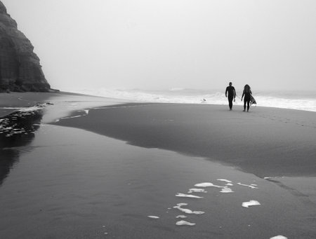 Couple walking on the beach in the misty morning. Black and white.