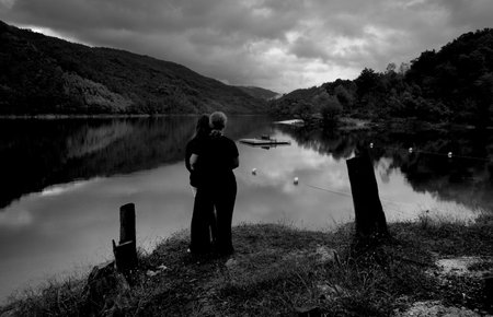 A black and white image of a senior couple fishing on a lake in Scotlandの写真素材