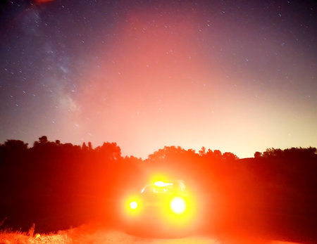 Night sky with stars and a car on the road in the countrysideの写真素材