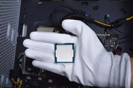 Picture of a hand wearing white gloves with a CPU chip placed on it.の写真素材