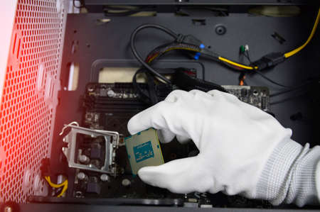 Image of a technician inserting a CPU chip onto a computer motherboard.の写真素材