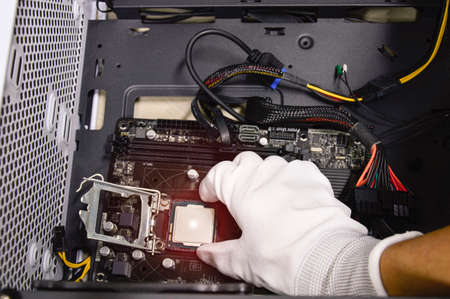 Image of a technician inserting a CPU chip onto a computer motherboard.の写真素材